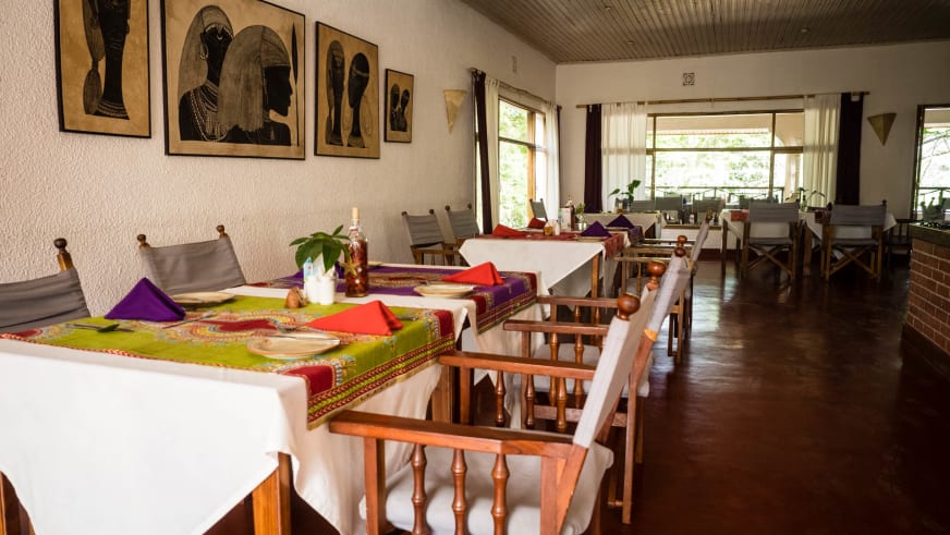 Gedeckte Tische mit afrikanischen Motiven im Restaurant der Ilboru Safari Lodge.
