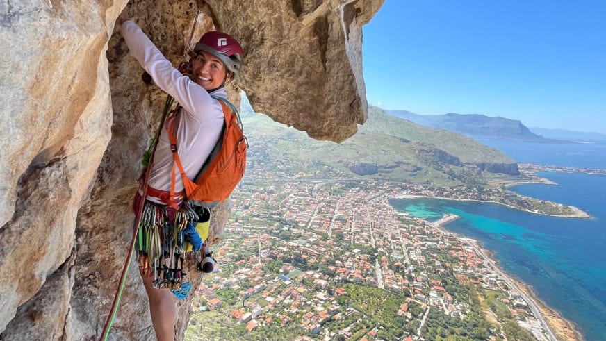 Bergführerin Monika Hümmer klettert an Kalksteinwand hoch über türkisblauem Meer.