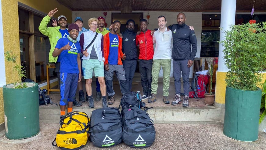 Trekking-Gruppe mit Ausrüstung vor dem Hauptgebäude der Ilboru Safari Lodge vor Mount Meru.