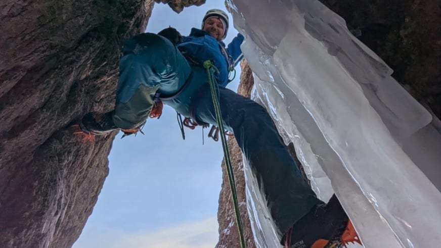 In einer steilen Eiswand klettert Bergführer Christoph Vonmetz mit Eisgeräten, Steigeisen und grünem Seil.