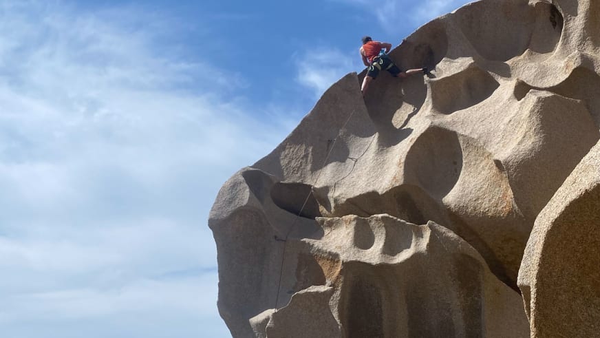 Bergführer Christoph Vonmetz klettert in roter Oberbekleidung an einer steilen Felswand aus hellem Gestein.