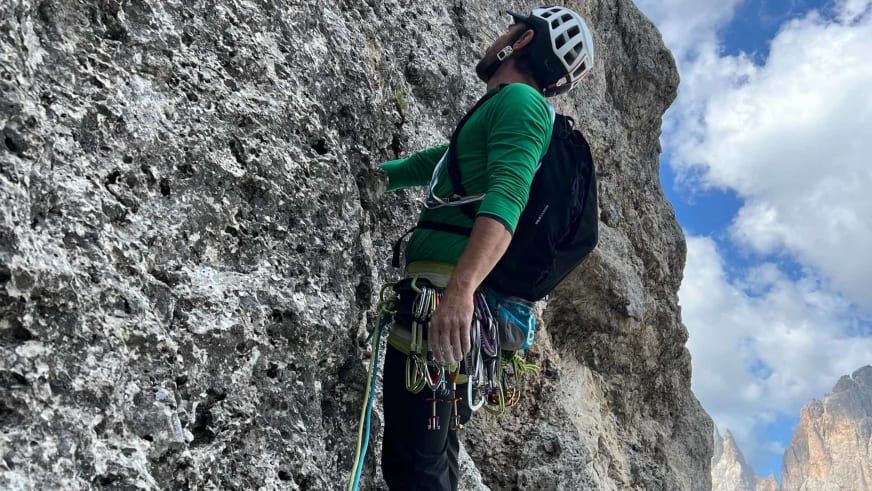 Bergführer Christoph Vonmetz trägt grünes Shirt und weißen Helm beim Klettern an grauer Kalksteinwand.