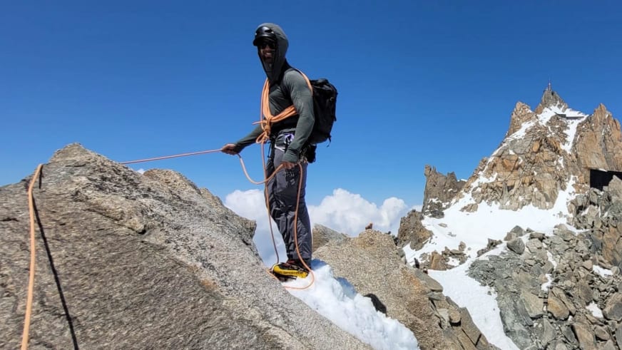Bergführer Joshua Wontroba steht mit orangem Kletterseil auf schneebedecktem Felsgrat in hochalpinem Gelände.