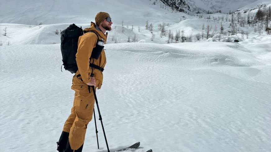 Bergführer Joshua Wontroba steht in gelber Winterbekleidung auf Tourenski in verschneiter Berglandschaft.
