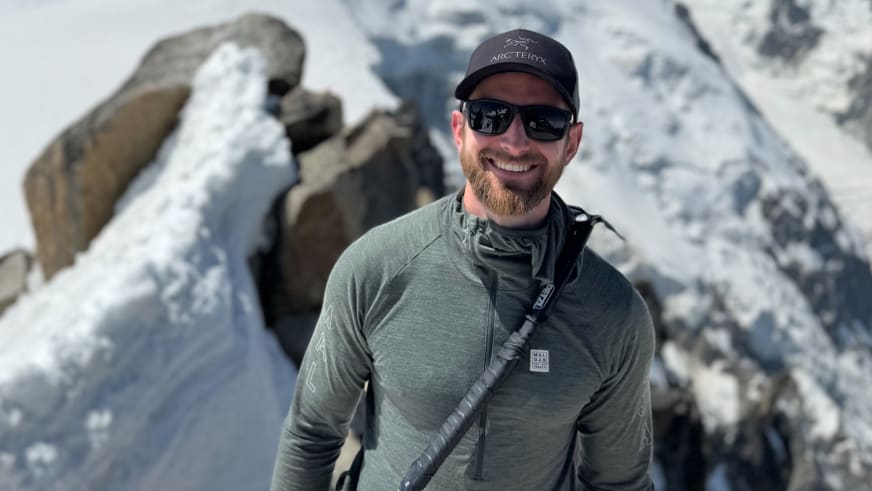 Winterportrait von Bergführer Joshua Wontroba in grüner Softshelljacke vor schneebedeckten Felsformationen.