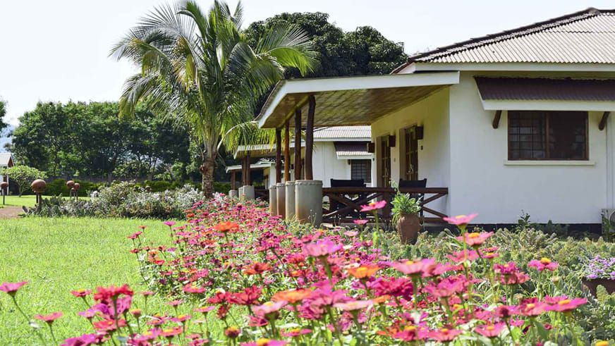 Einstöckiges Gebäude mit Veranda und Blumengarten in der tropischen Anlage der AMEG Lodge.