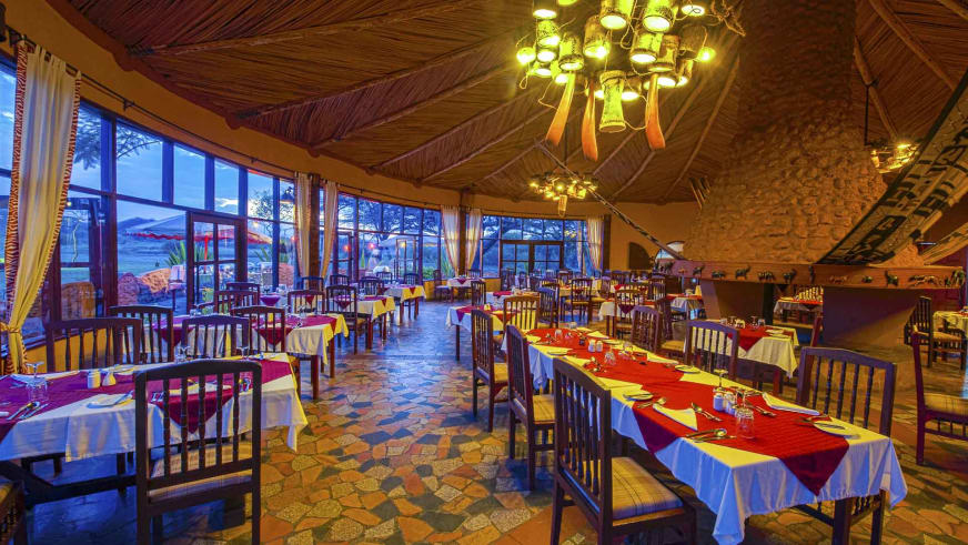 Restaurantbereich der Amboseli Sopa Lodge mit gewölbter Holzdecke, Steinwänden und gedeckten Tischen.
