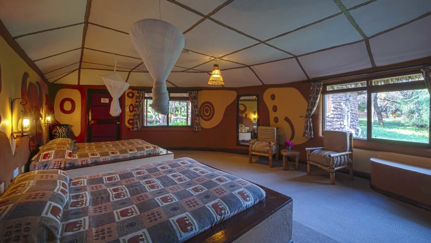 Twinbett-Zimmer in der Amboseli Sopa Lodge mit bunten geometrischen Tagesdecken und afrikanischen Wandmalereien.
