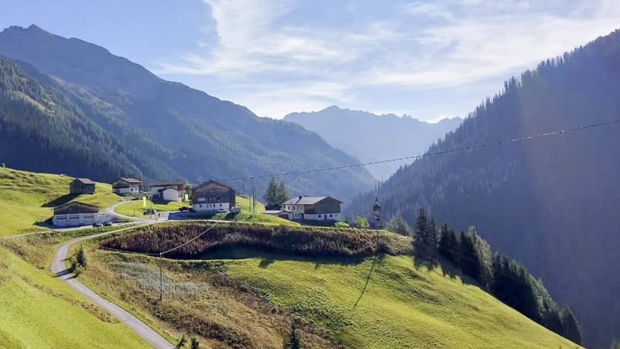 Blick über die Ortschaft Kaisers im Lechtal mit dem Edelweisshaus und der Seilbahn-Talstation inmitten grüner Almwiesen.
