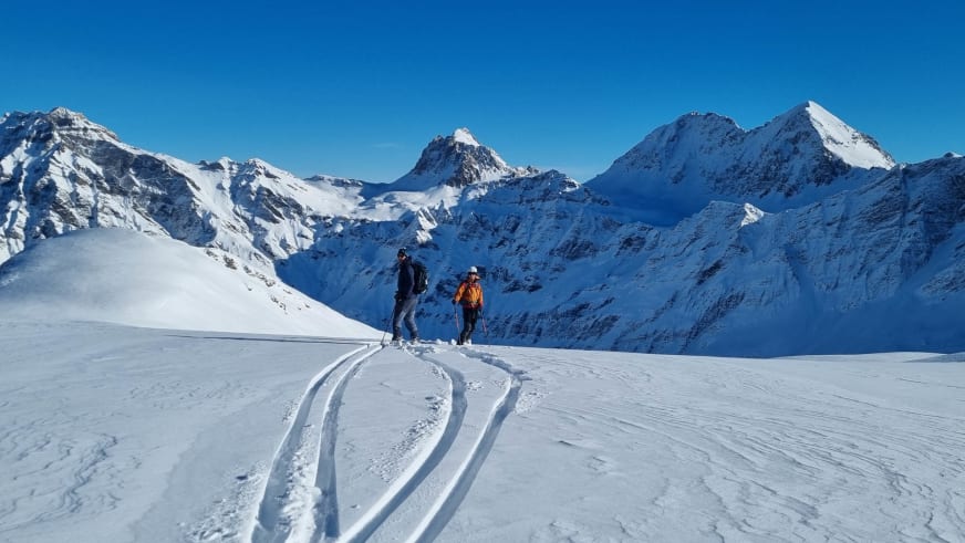 Zwei Skitourengeher auf Gletscherfläche im Tourengebiet des Hotel Camana mit Bergkette der Adula-Alpen im Hintergrund.