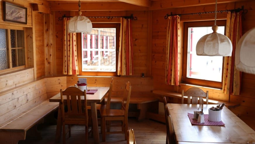 Holzvertäfelter Speiseraum der Oberwalder Hütte mit Eckbank und rot-weiß karierten Tischdecken.