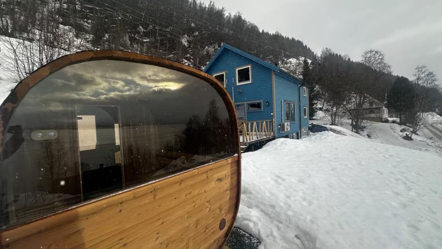 Außensauna mit Panoramafenster vor dem Lyngen Blue House in verschneiter Winterlandschaft.