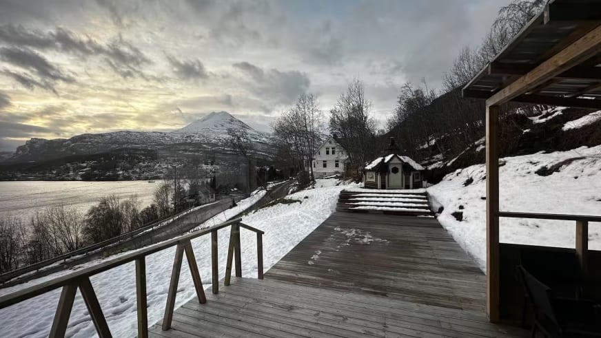 Terrasse des Lyngen Blue House mit Panoramablick auf den verschneiten Fjord und die Berge.