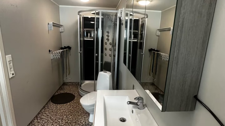 Badezimmer im Lyngen Blue House mit runder Duschkabine und modernem Waschbecken.