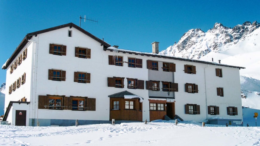 Die Heidelberger Hütte steht verschneit inmitten der winterlichen Silvretta-Bergwelt auf 2.264 m Höhe.