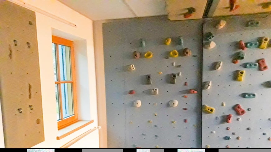 Kletterraum der Jamtalhütte mit bunter Boulderwand und verschiedenfarbigen Klettergriffen.