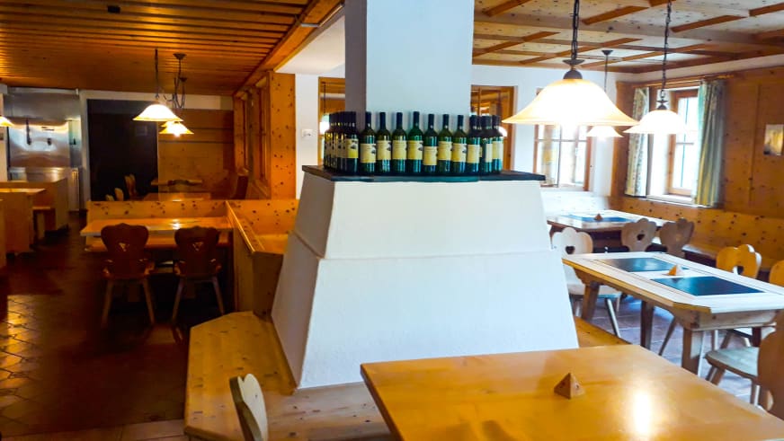 Gastraum der Jamtalhütte mit weißem Kachelofen, Holztischen und traditioneller Alpenausstattung.