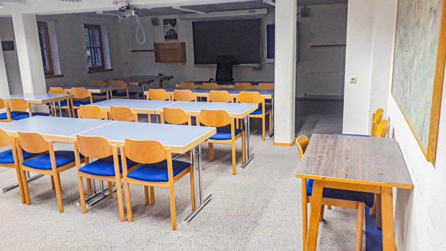 Seminarraum der Jamtalhütte mit Tischen, Stühlen und Beamer für Bergführer-Ausbildung.