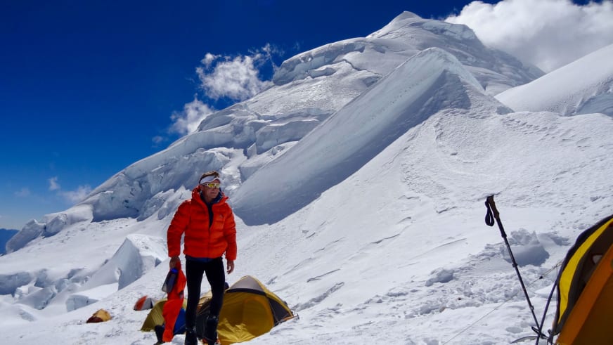 Bergführer Marcel Roßbach steht in roter Winterjacke vor einem gelben Zelt im verschneiten Expeditionslager.