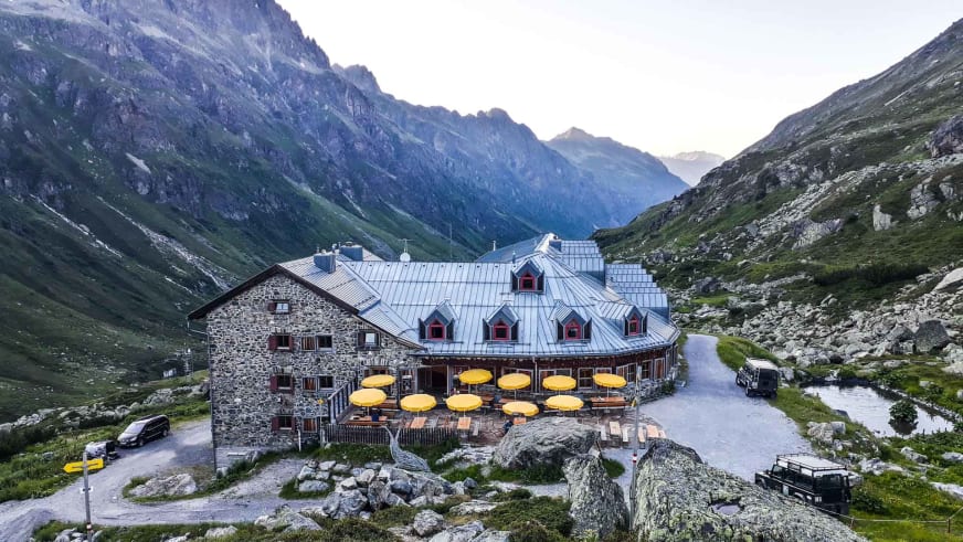 Luftaufnahme der Jamtalhütte mit großer Sonnenterrasse und gelben Sonnenschirmen im Jamtal.