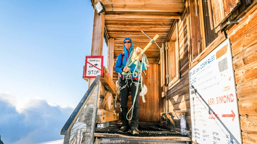Bergsteiger mit Kletterausrüstung vor dem Eingang des Refuge des Cosmiques bei Sommerwetter.