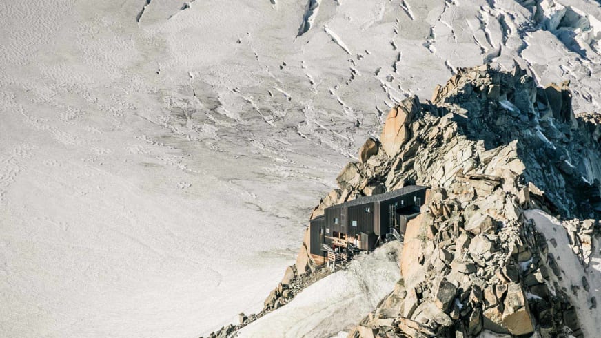 Luftbild zeigt das Refuge des Cosmiques auf schmalem Felsgrat zwischen Gletscherspalten.