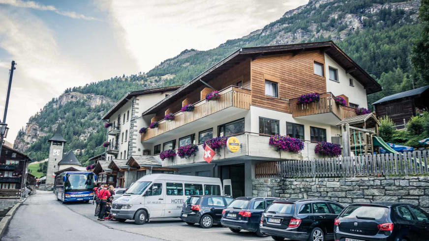 Außenansicht des Hotel Bergfreund in Herbriggen mit typischer Alpenarchitektur und Hotelbus im Mattertal.