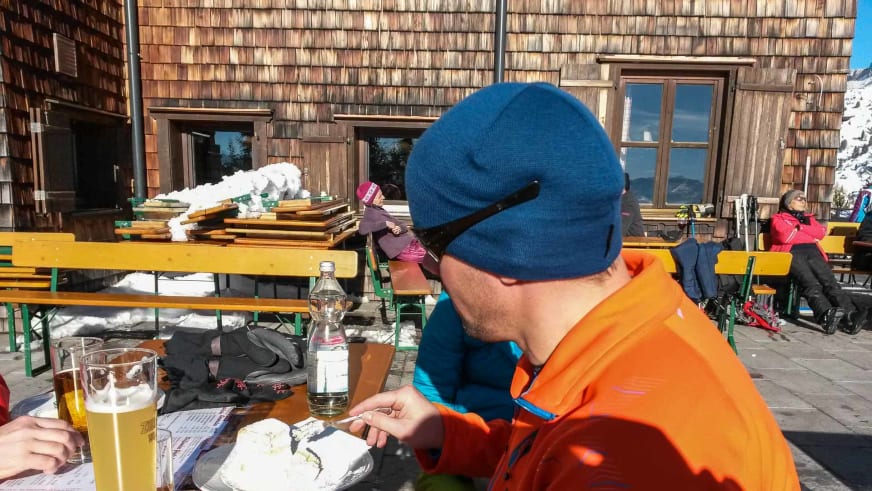 Skitourengeher bei der Brotzeit auf der Terrasse der Erfurter Hütte mit traditionellen Bierbänken.