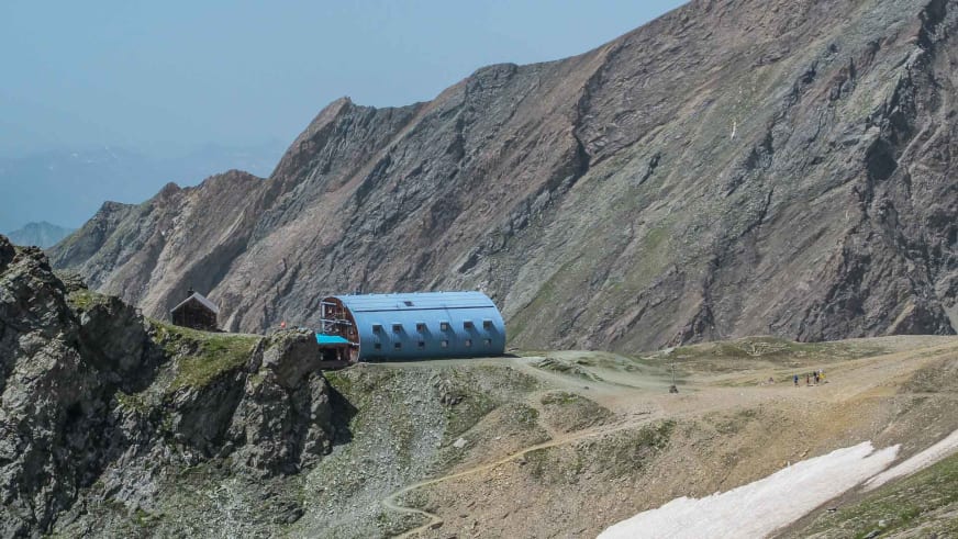 Panoramablick auf die moderne Stüdlhütte mit silbernem Blechdach auf felsigem Plateau in hochalpiner Lage.