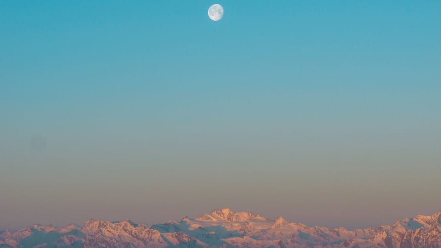 Schneebedeckte Berggipfel mit Alpenglow und Vollmond während der Abenddämmerung beim Rifugio Città di Mantova.
