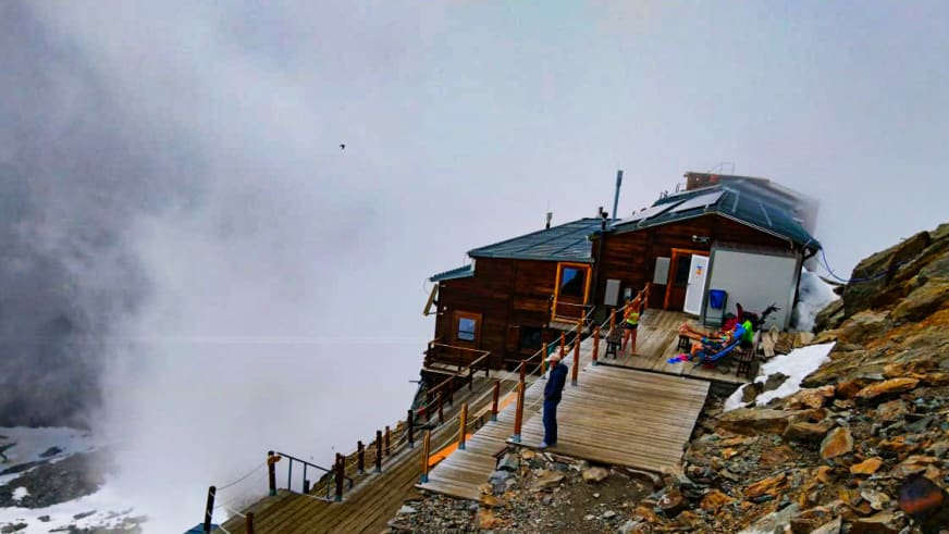 Das Rifugio Città di Mantova steht als modernes Holzgebäude auf einem Felsplateau in hochalpiner Lage.