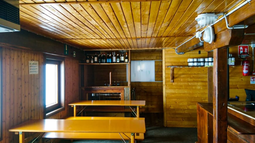 Gastraum mit Holztischen und Bänken im Rifugio Città di Mantova zeigt traditionelle Holzverkleidung.