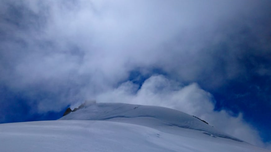 Verschneite Bergkuppe ragt aus Wolkendecke hervor in der Nähe der Capanna Margherita.