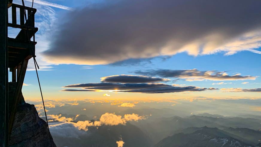 Holzplattform der Capanna Margherita mit Panoramablick über Wolkendecke und Bergkämme.