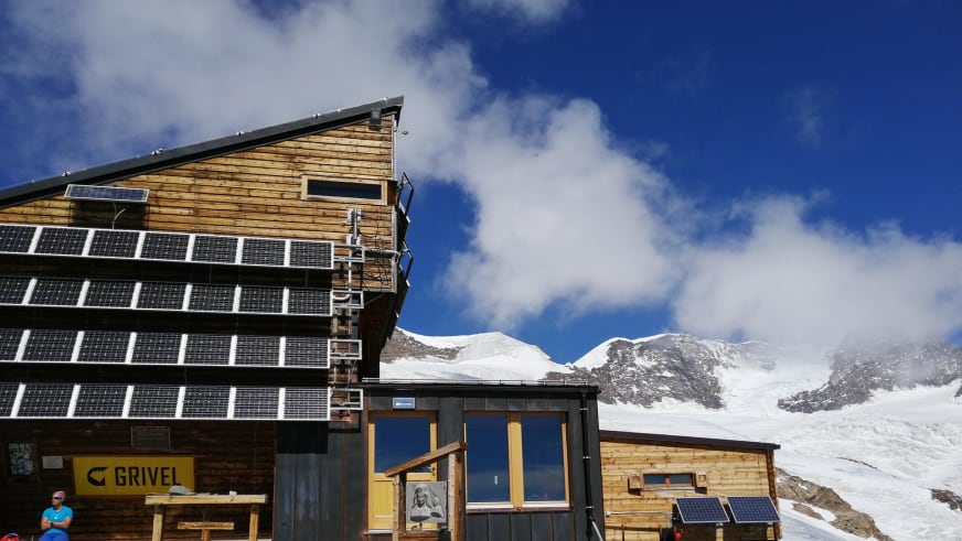 Außenansicht des Rifugio Quintino Sella al Felik mit moderner Holzfassade und Solarpaneelen in den Walliser Alpen.
