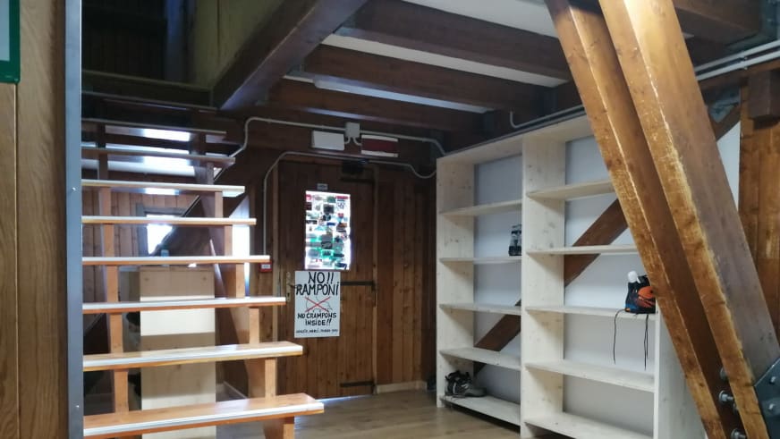 Aufbewahrungsraum im Rifugio Quintino Sella al Felik mit Holzregalen und traditioneller Balkenkonstruktion.