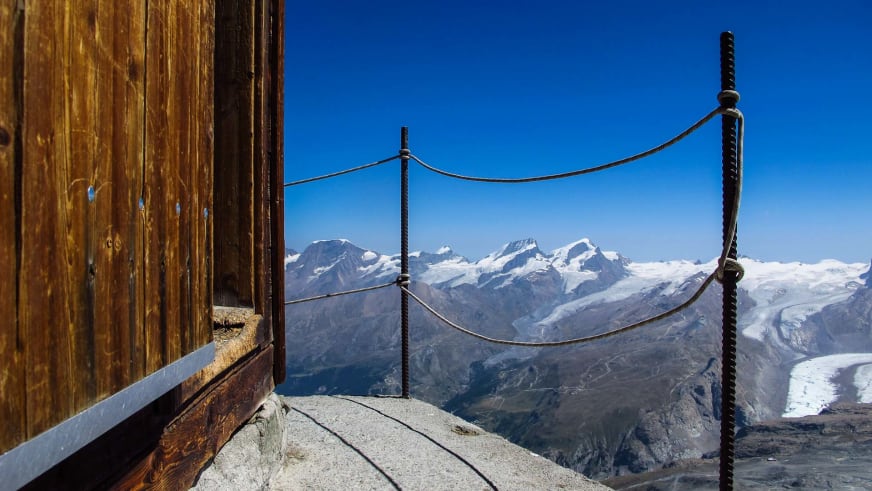 Blick von der Terrasse der Hörnlihütte über das Tal auf schneebedeckte Bergkette und Gletscher.