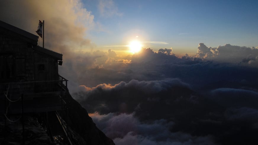 Sonnenaufgang an der Mittellegihütte mit goldenen Wolken über dem Tal der Berner Alpen.