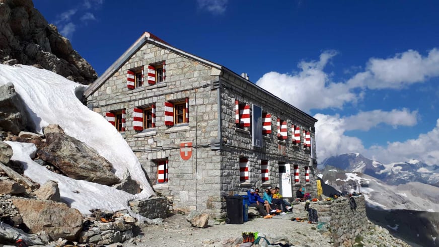 Die Rothornhütte steht zwischen Gletschern und Schneezungen in der hochalpinen Landschaft der Walliser Alpen.