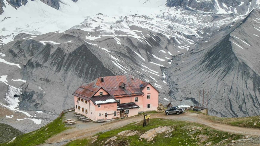 Die Schaubachhütte steht auf einem grünen Plateau vor schneebedeckten Berghängen im Ortlergebiet.