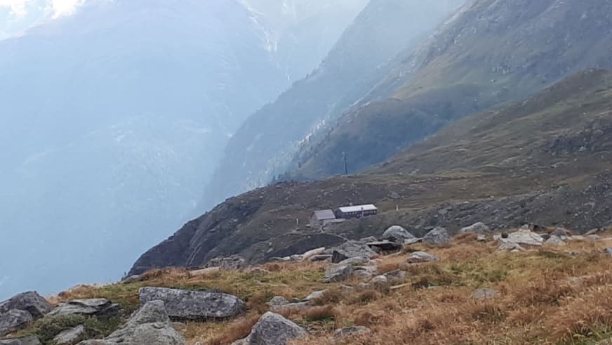 Panoramablick auf die Essener-Rostocker Hütte inmitten herbstlich gefärbter Almwiesen im Hochgebirge der Hohen Tauern.