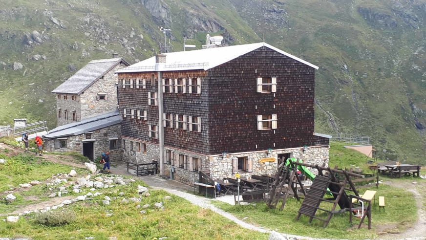 Die Essener-Rostocker Hütte zeigt typische Alpenarchitektur mit Holzschindelfassade und Natursteinmauerwerk im Sockelber