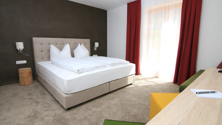 Modernes Hotelzimmer im Alpinhotel Berchtesgaden mit Doppelbett und hellem Holzmobiliar.
