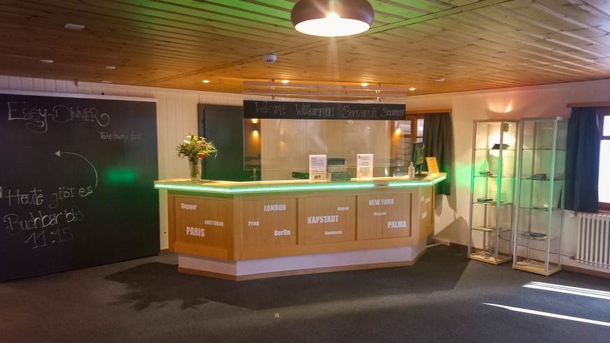 Rezeptionstheke der Eiger Lodge mit geschwungener Form und grüner LED-Beleuchtung.