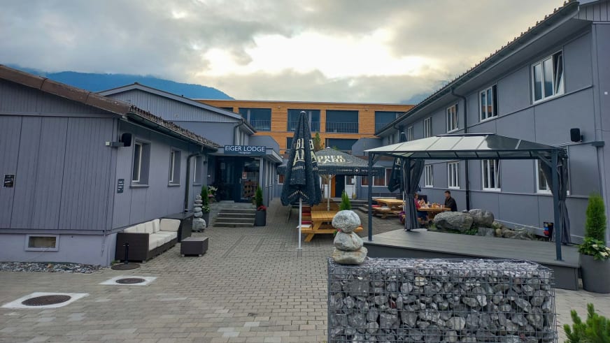 Innenhof der Eiger Lodge mit gepflasterten Steinplatten und überdachter Terrasse für Gäste.