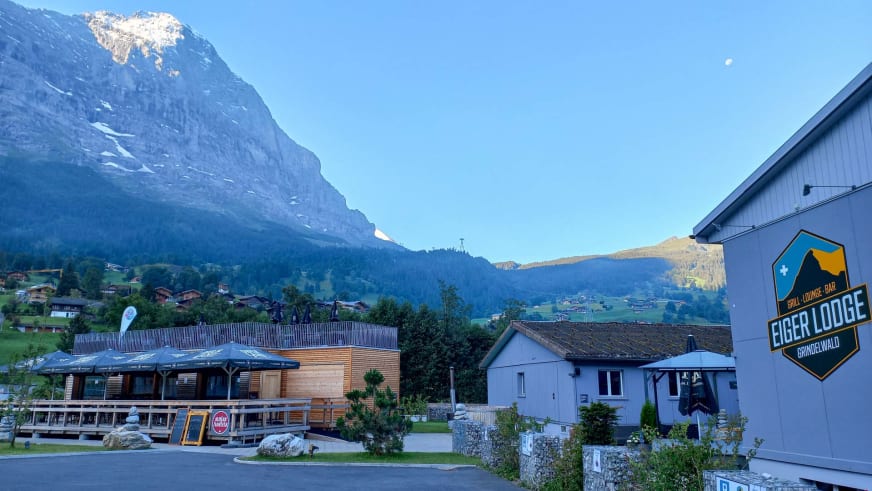 Abendansicht der Eiger Lodge mit beleuchteter Fassade und Blick auf schneebedeckte Felswände.