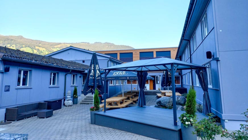Überdachte Terrasse der Eiger Lodge mit dunklem Pavillon und Holztischen für den Außenbereich.