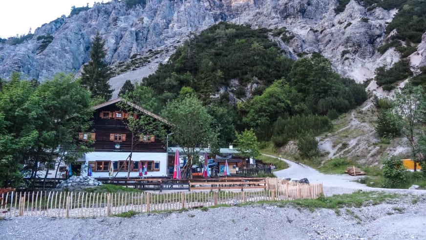 Die Wimbachgrieshütte zeigt traditionelle Alpenarchitektur mit großer Holzterrasse vor steiler Kalksteinwand.