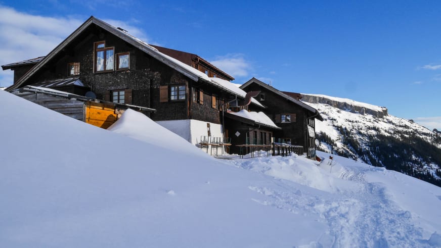Die Schwarzwasserhütte steht tief verschneit auf 1.620 m in den winterlichen Allgäuer Alpen.