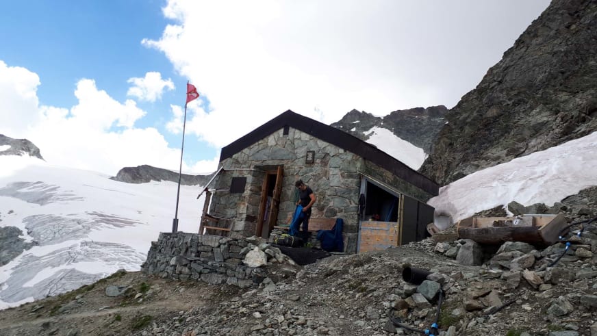 Das Arbenbiwak steht auf felsigem Untergrund zwischen Gletschern und schneebedeckten Gipfeln auf 3224 m Höhe.